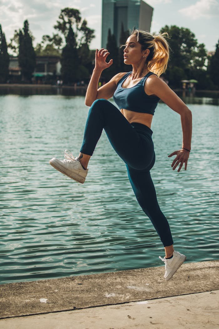 Active woman performing a fitness jump near a lake in Ciudad de México.